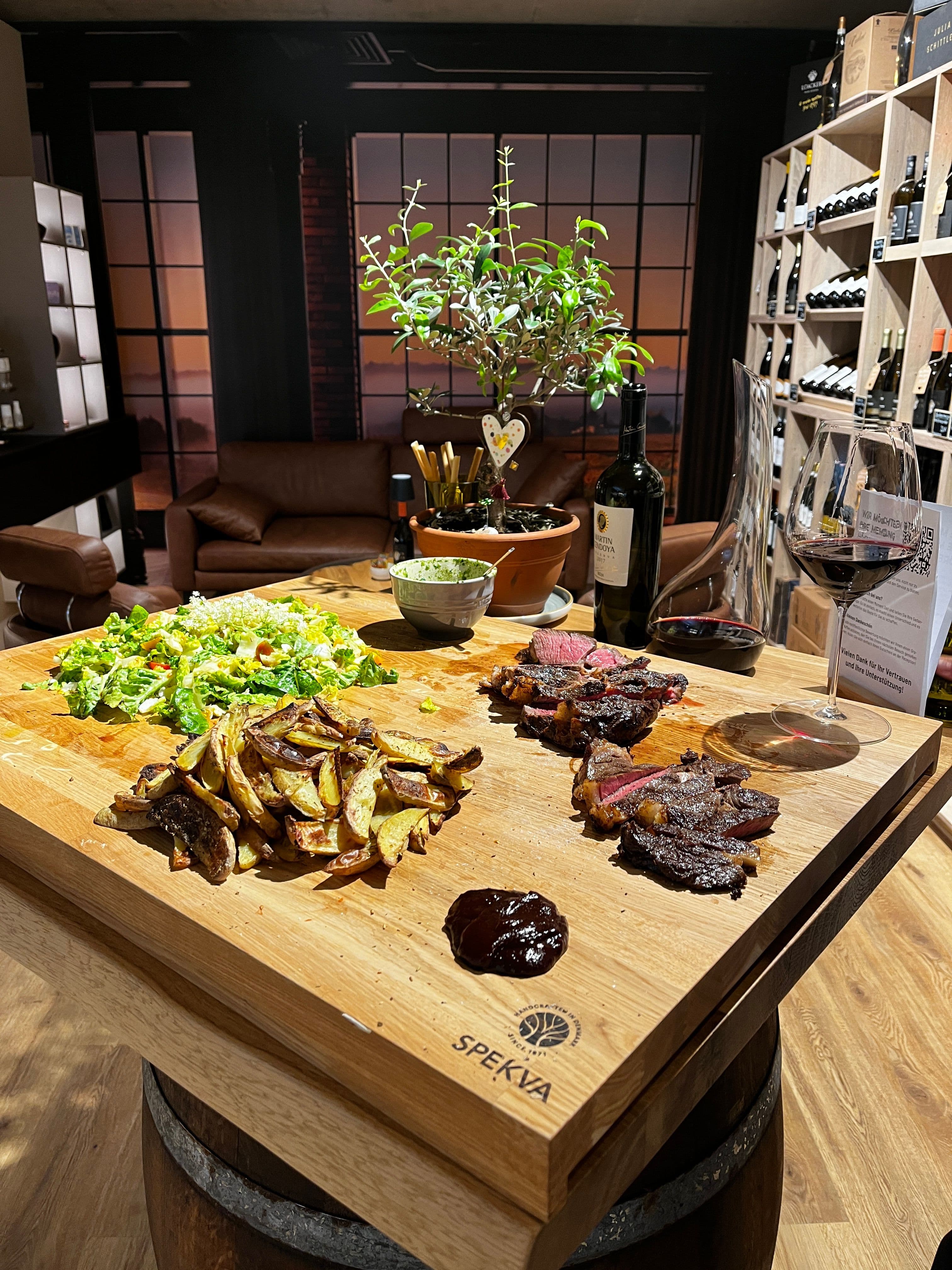 Spekva-Holzbrett aus Eiche mit Wein und Speisen im Vinothek-Bereich des Thoki Studios