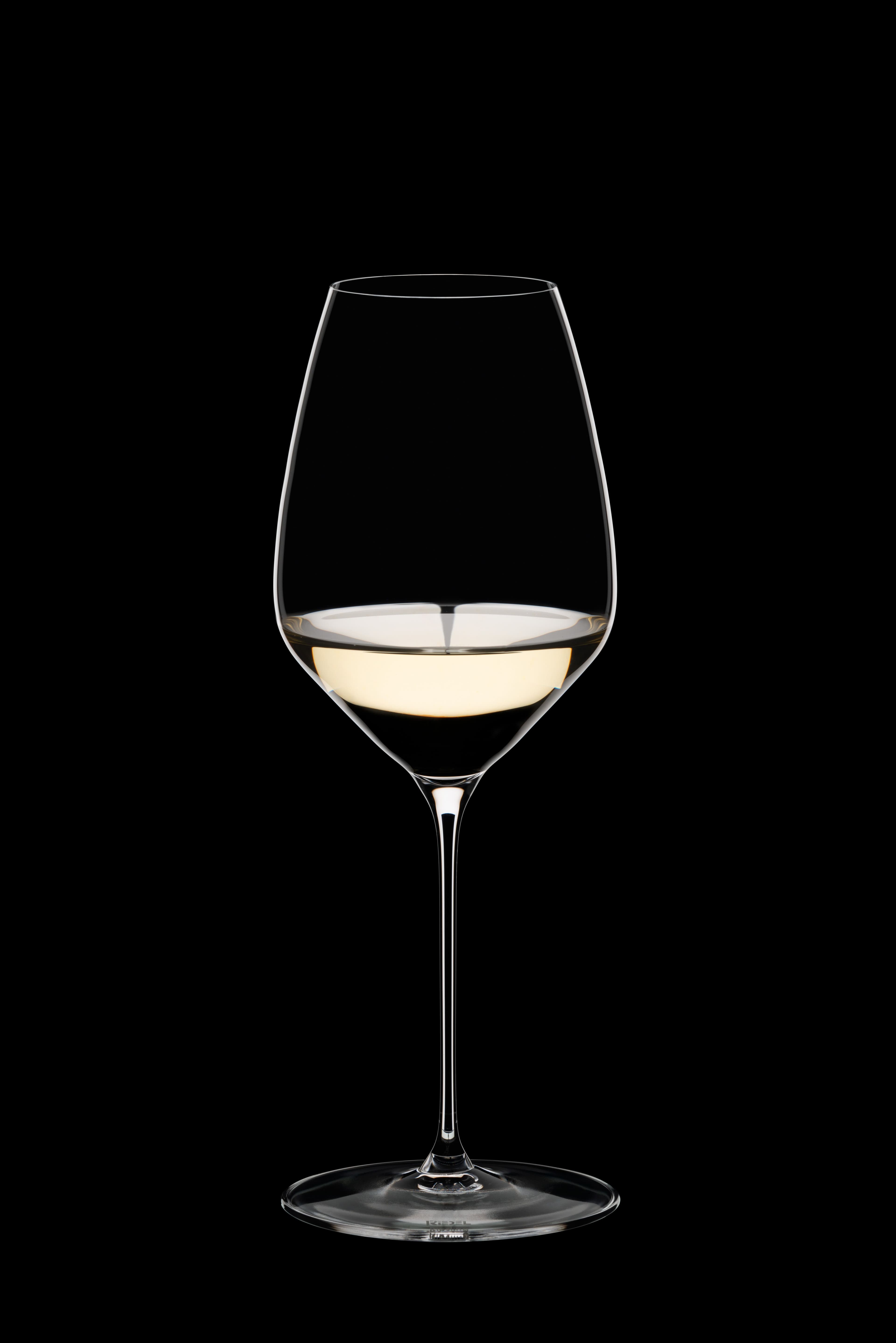 Riedel Veloce Riesling-Glas mit Weißwein vor schwarzem Hintergrund